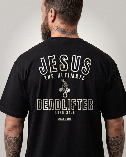 Jesus The Ultimate Deadlifter heavyweight tee, Black, 6 oz Ultra Cotton boxy classic cut, plain front and collegiate JESUS THE ULTIMATE DEADLIFTER back print, Luke 24:6