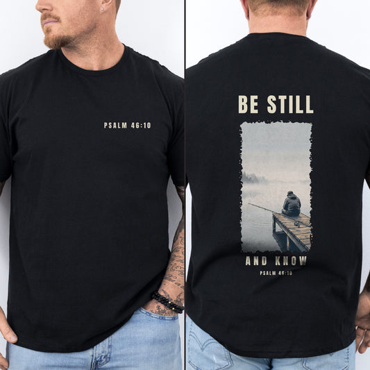Be Still And Know Christian fishing shirt, Black, worn by a man, front chest verse badge with misty pier poster back print, Psalm 46:10