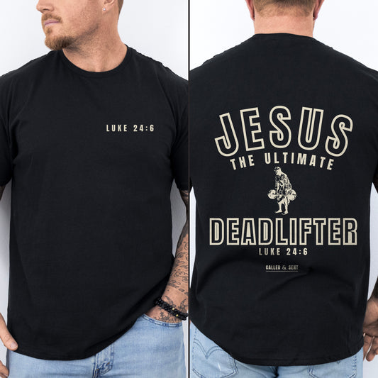 Jesus The Ultimate Deadlifter Christian shirt, Black, worn by a man, front chest verse badge with collegiate JESUS THE ULTIMATE DEADLIFTER back print, Luke 24:6
