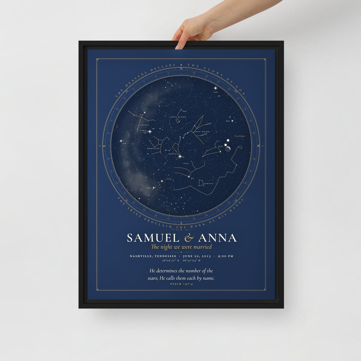A hand holding the framed canvas night sky print to show its size and the slim black frame