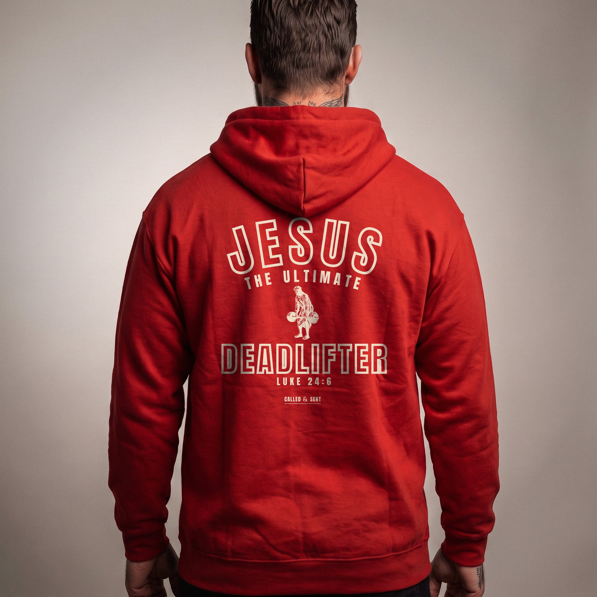 Jesus the Ultimate Deadlifter Christian hoodie, Red, worn by a man, back view, Luke 24:6 back print